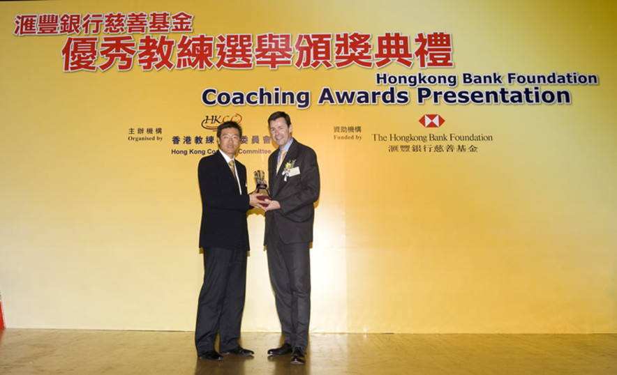 <p>帶領香港足球隊勇奪2009東亞運動會（東亞運）金牌的教練金判坤（左），從香港上海滙豐銀行有限公司香港區總裁馬凱博（右）手上接過最佳隊際運動教練獎。其他東亞運的教練亦獲邀出席頒獎禮，接受在場嘉賓的掌聲嘉許。</p>
