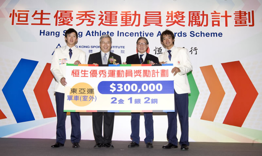 <p>香港体育学院主席李家祥博士(左二)及中国香港体育协会暨奥林匹克委员会会长霍震霆(右二)，在「恒生优秀运动员奖励计划」颁奖典礼上，颁发现金奖励予第五届东亚运动会单车项目奖牌得主，包拾黄金宝(右一)及郭灏霆(左一)。</p>
